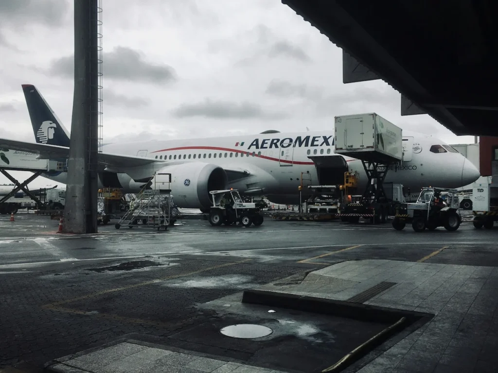 An Aeroméxico plane parked at a gate under a cloudy sky