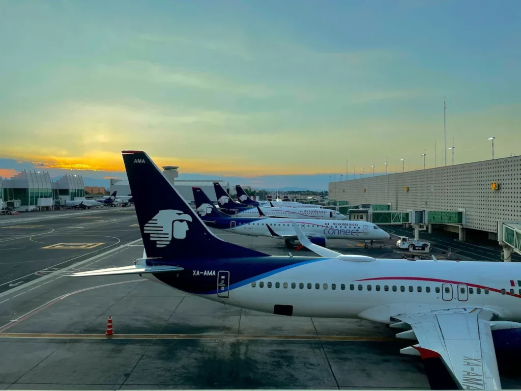 Multiple Aeroméxico passenger planes parked in a row at airport gates during sunset