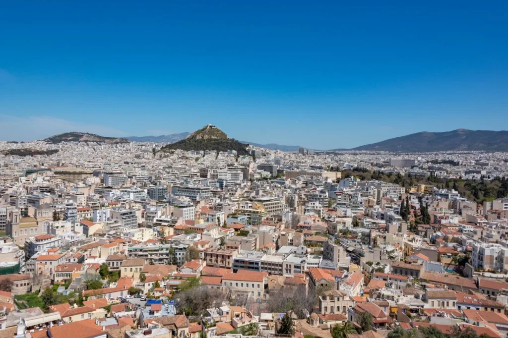 A wide panoramic view of the Athens cityscape with Mount Lycabettus in the center