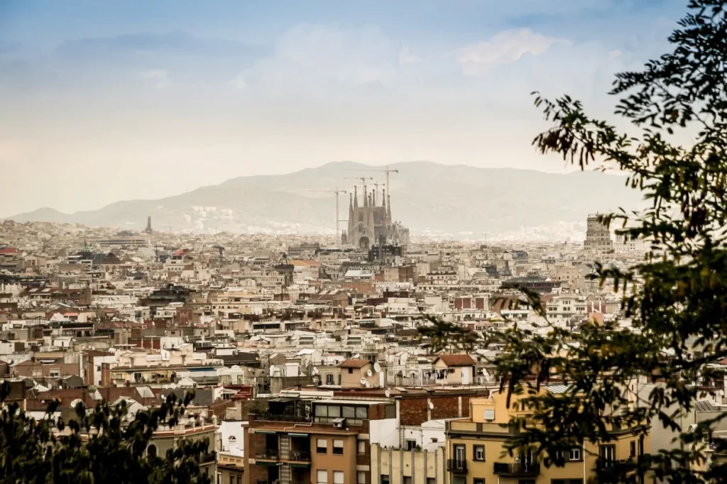 Distant skyline view of Barcelona city buildings and the Sagrada Familia basilica under hazy skies