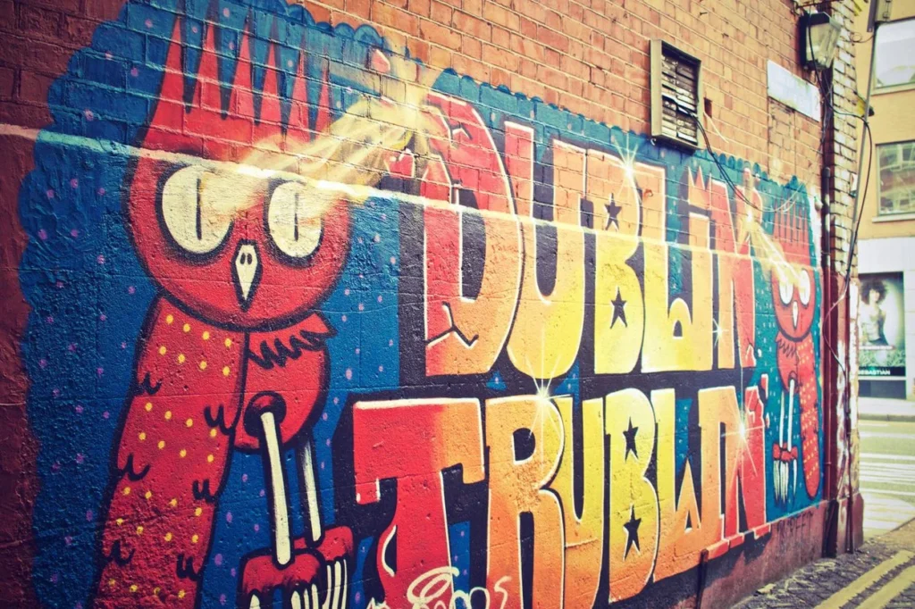 Colorful graffiti mural reading "DUBLIN" with red owl characters painted on a brick wall