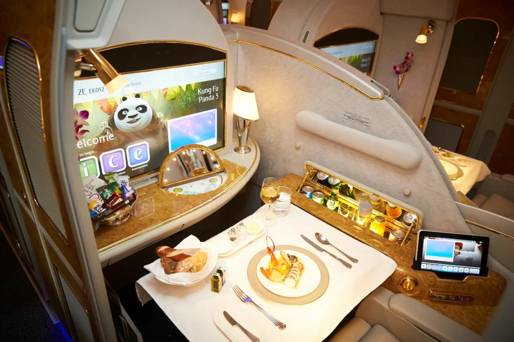 Emirates first-class airplane suite with gourmet dinner tray and inflight entertainment screen