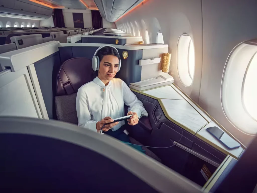 Passenger wearing headphones inside an Etihad Airways business class suite by the windows