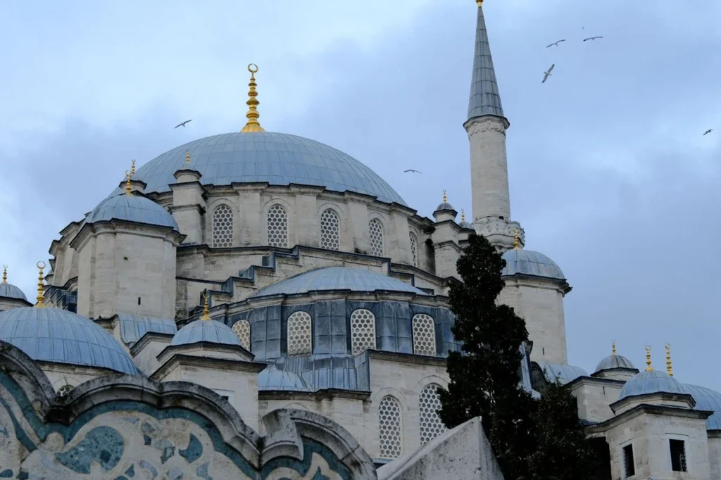 The central dome and a stone minaret of the Fatih Mosque in Istanbul under a cloudy sky
