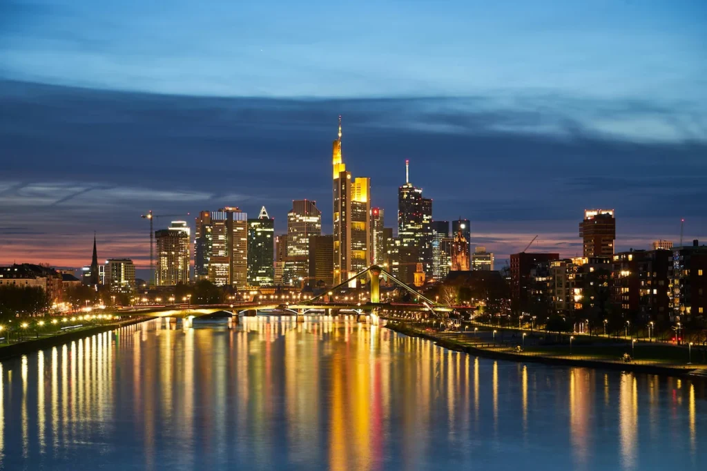 The illuminated Frankfurt skyline reflecting in the Main River at dusk