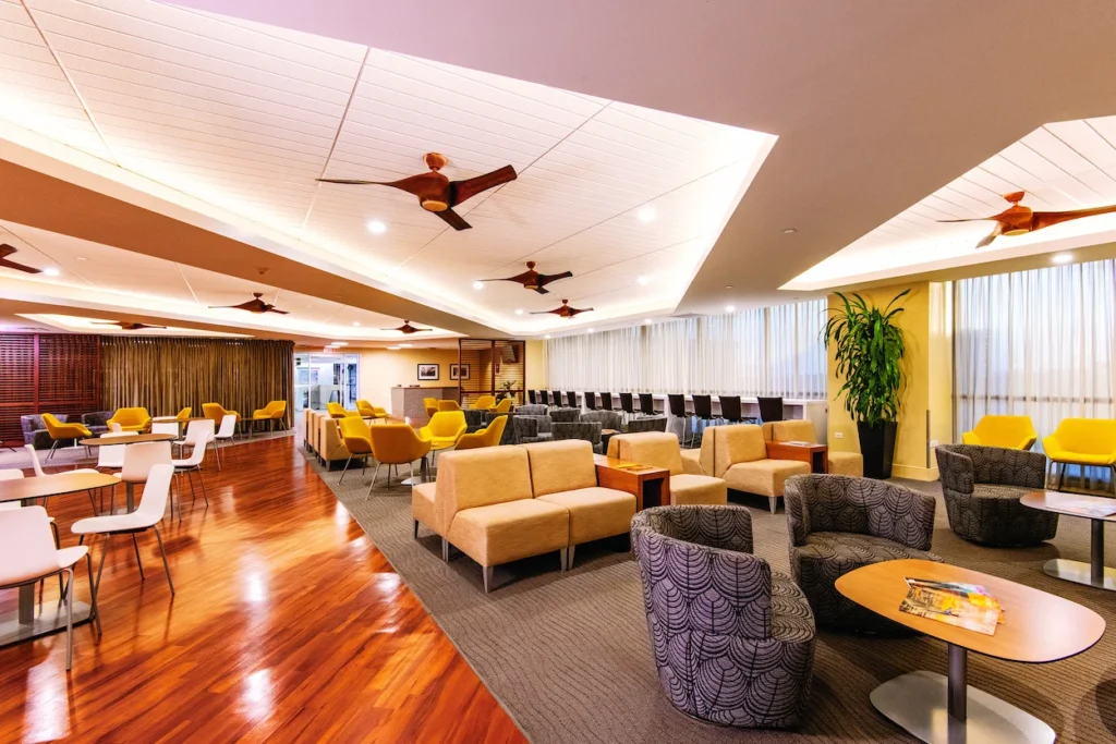 Hawaiian Airlines Plumeria Lounge interior with modern seating areas, wood flooring, and ceiling fans