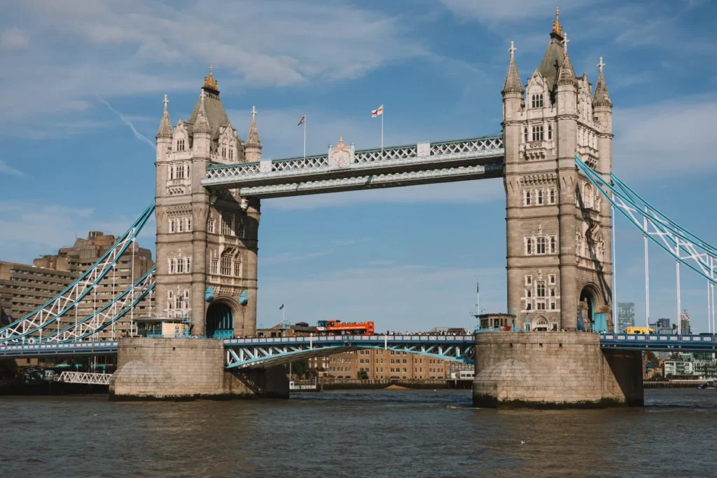 Tower Bridge standing over the River Thames under a blue sky with a red bus crossing