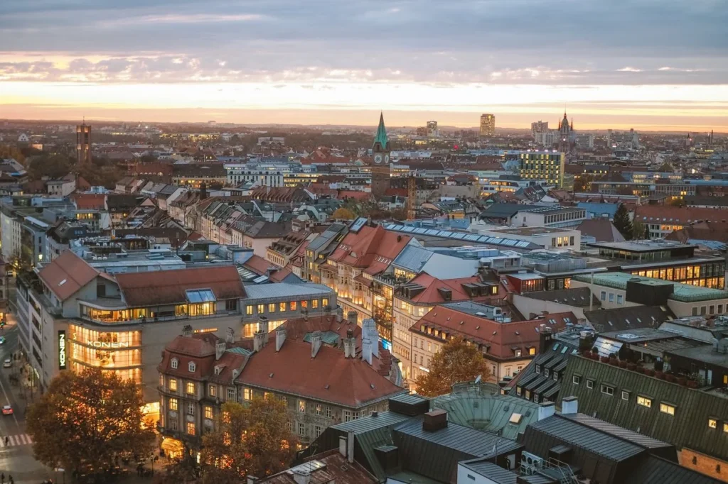 High-angle view of Munich's cityscape with red tile roofs and church spires at sunset