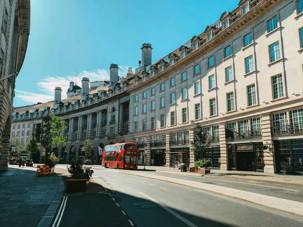 A classic red double-decker bus driving down the curved stone buildings of Regent Street