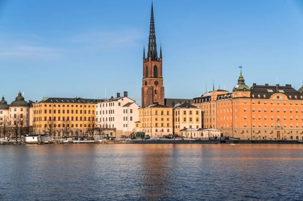 Riddarholmen Church and colorful historic buildings along the Stockholm waterfront under a blue sky