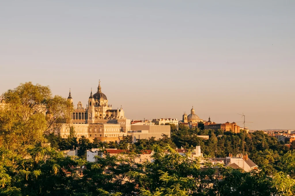 Distant view of the Royal Palace and Almudena Cathedral in Madrid framed by green trees