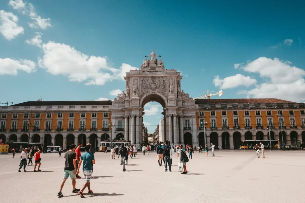 The grand Rua Augusta Arch and yellow buildings of Praça do Comércio filled with people in Lisbon