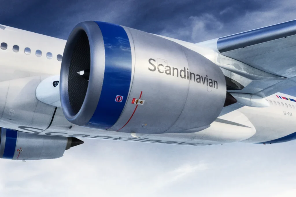 A close-up of a silver SAS airplane engine with blue trim flying mid-air