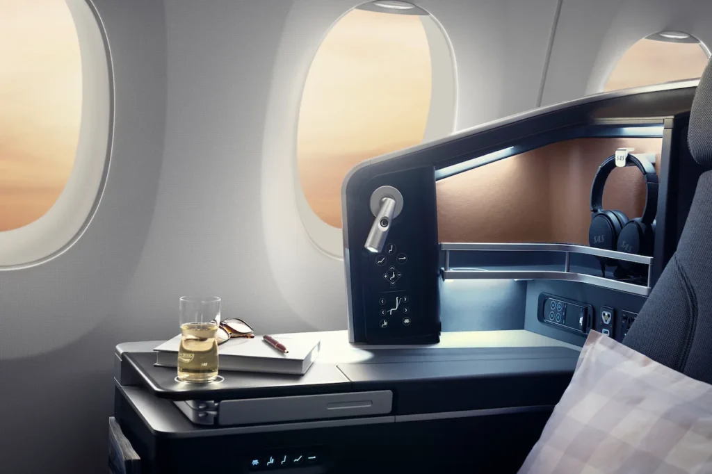 An SAS business class suite console table with a drink and sunglasses by airplane windows