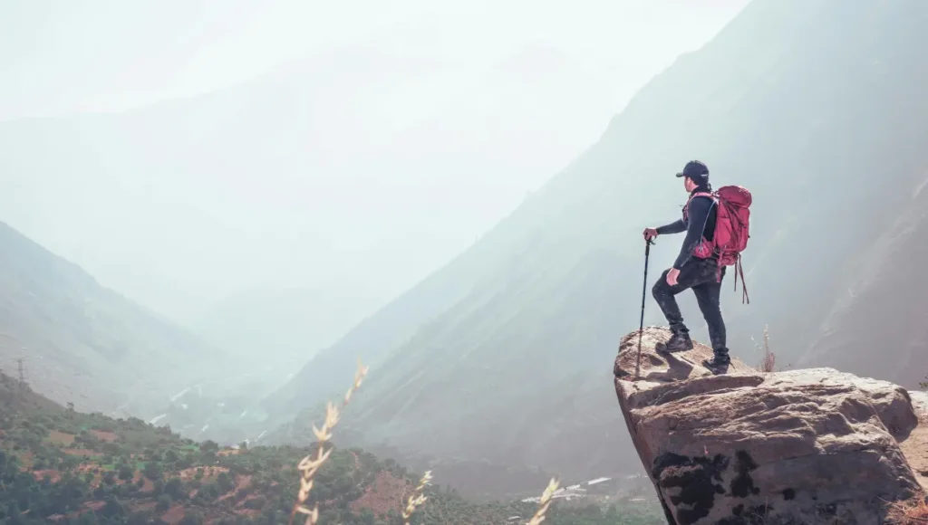 A person standing on the edge of a cliff after climbing the mountain