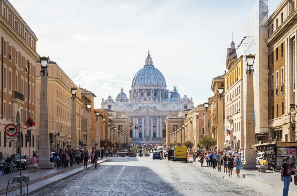 A wide city street lined with buildings leading toward a large domed cathedral