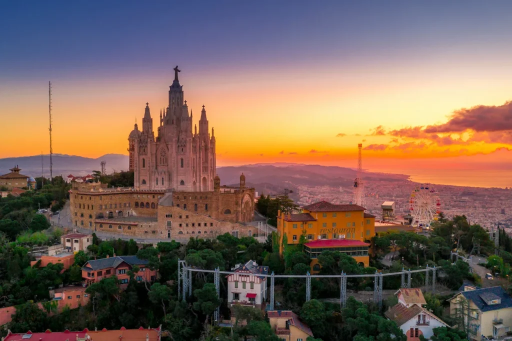 The illuminated Sagrat Cor church on Mount Tibidabo overlooking the Barcelona skyline at dusk