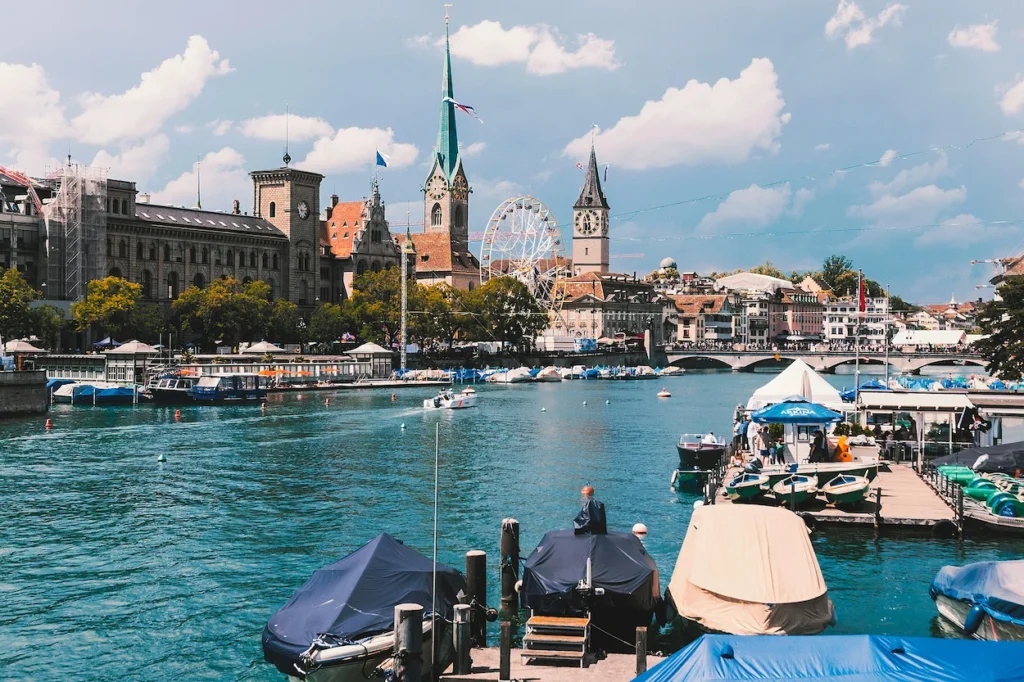 The Limmat River waterfront in Zurich with Fraumünster Church and a Ferris wheel