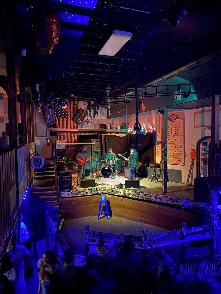 Live band performing on stage at Chelsea's Corner Cafe under colorful lighting.