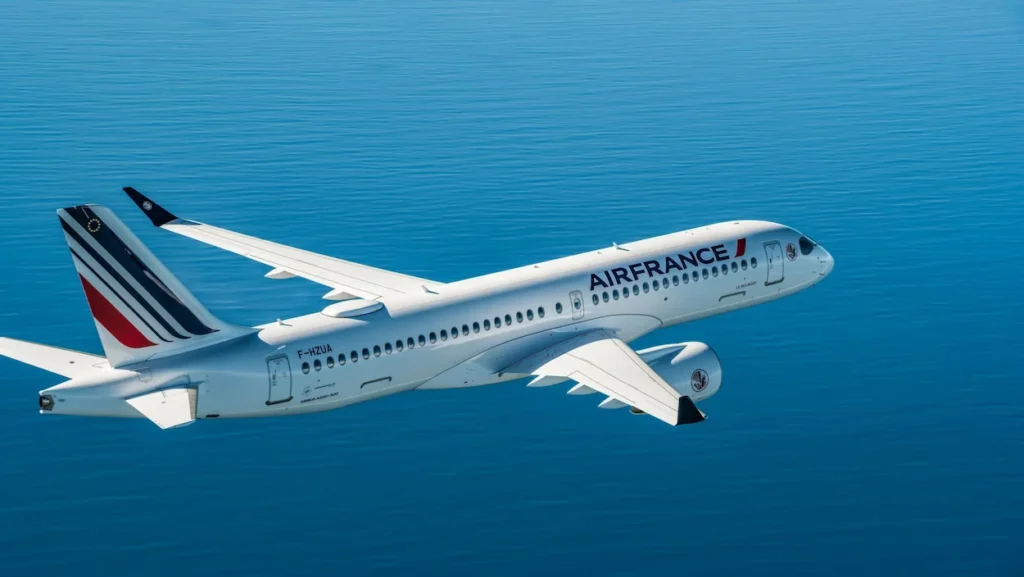 An Air France Airbus A220 passenger plane flying over bright blue water
