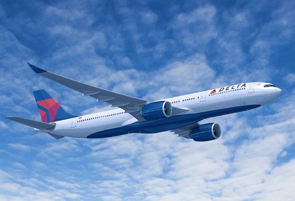 A Delta Air Lines passenger plane flying through a blue sky with scattered clouds