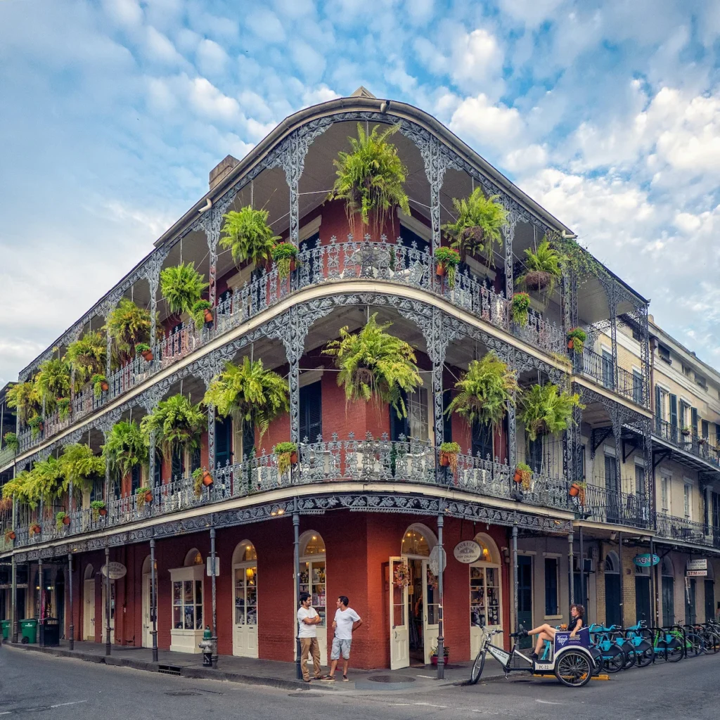 Historic wrought-iron balcony decorated with hanging plants in New Orleans