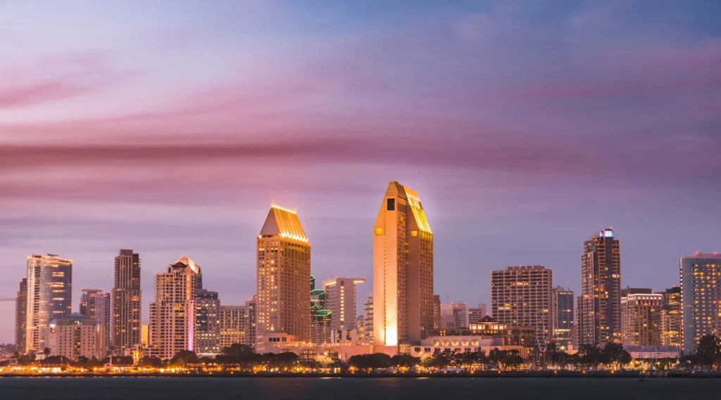 The San Diego skyline lit up across the bay at sunset