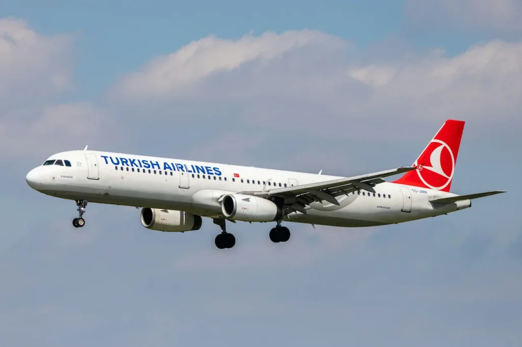 Turkish Airlines Airbus passenger airplane landing with its wheels down against a cloudy sky