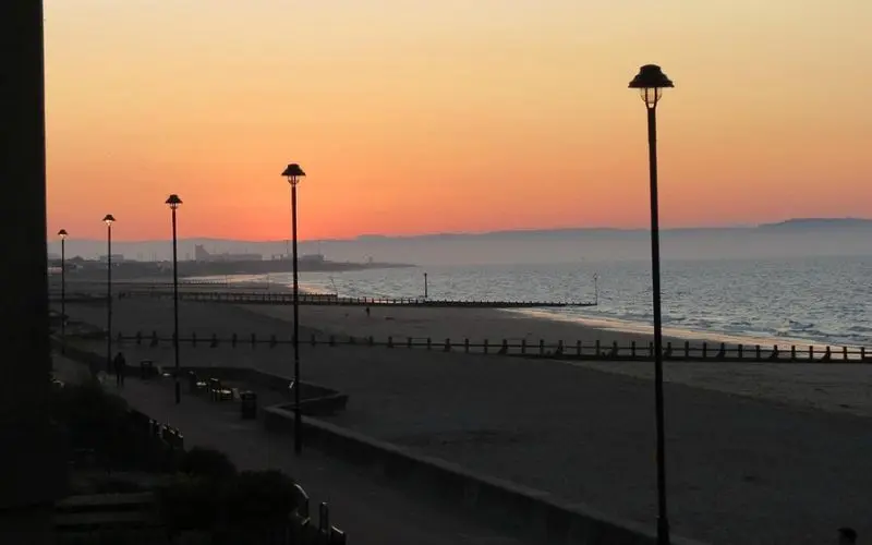 Sunset over Portobello Beach with street lamps.