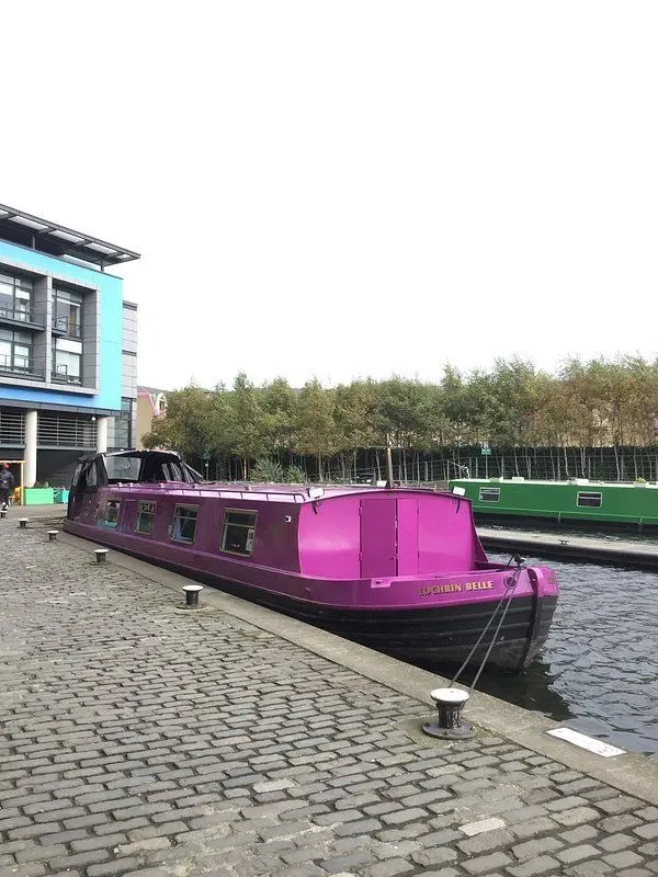 The purple Lochrin Belle canal boat docked by the water.