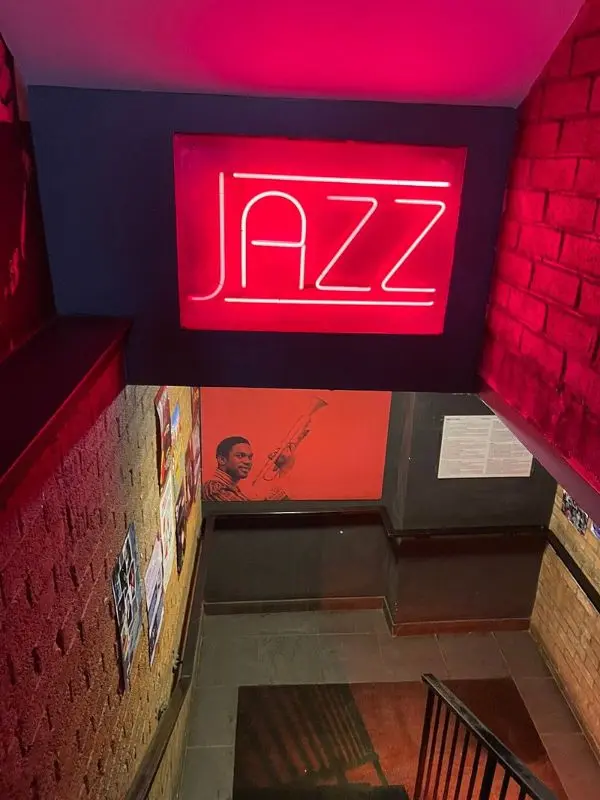 A neon jazz sign above stairs at The Jazz Bar.