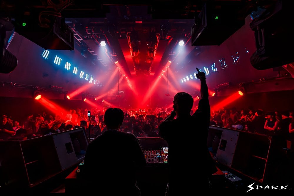 DJ performing for a packed crowd at Spark Club KL under red stage lights.