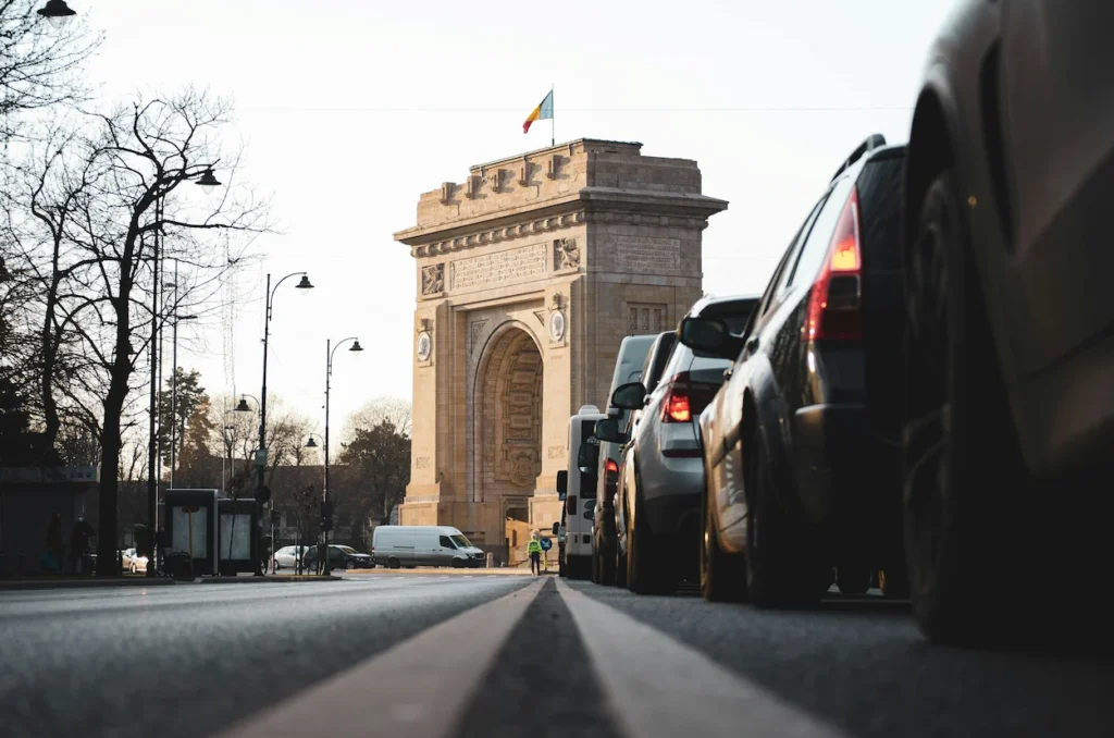 Low angle view of traffic lined up on a street leading toward the Arcul de Triumf in Bucharest