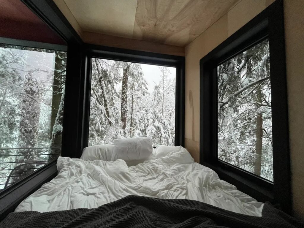 The bed surrounded by giant glass windows offers amazing views, whether it’s snow or autumn leaves falling outside