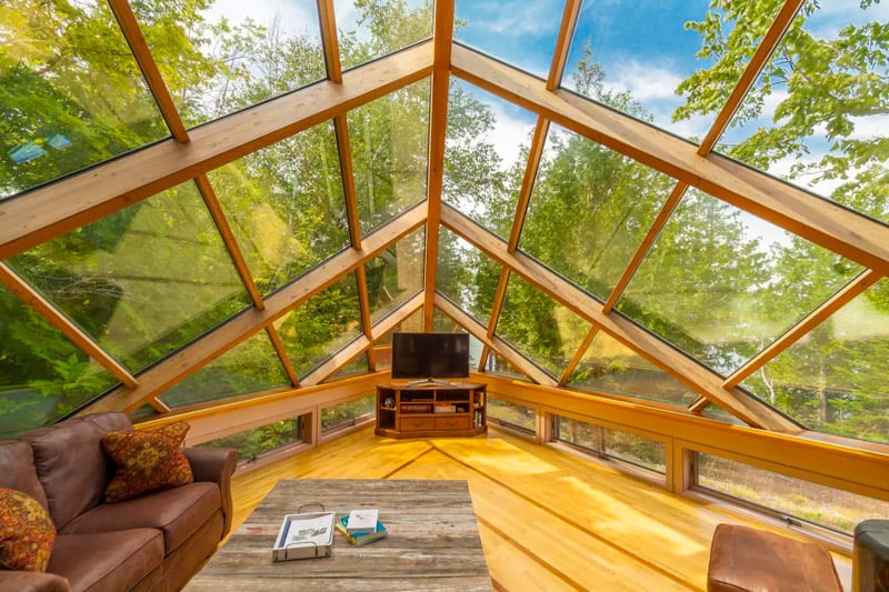 Relax in this incredible sunroom with floor-to-ceiling windows that bring the outdoors right inside