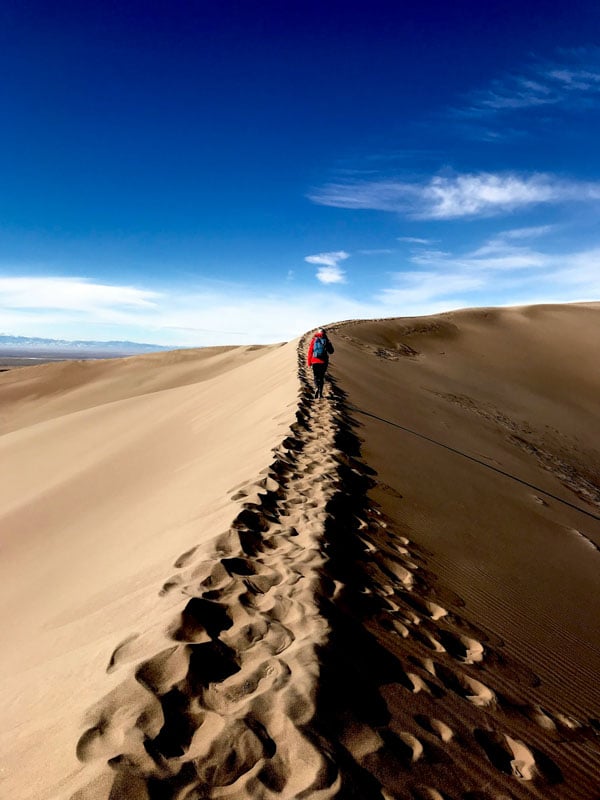 Great Sand Dunes National Park features towering dunes and stunning mountain views, ideal for hiking and sandboarding.