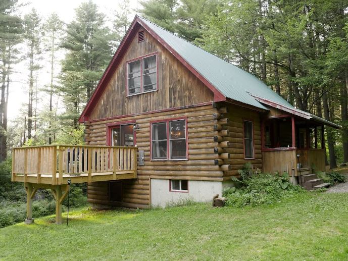 Log cabin rental in Stowe, VT surrounded by towering pines