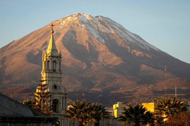 A Peruvian mountain with a church in the foreground, set against the Andes.