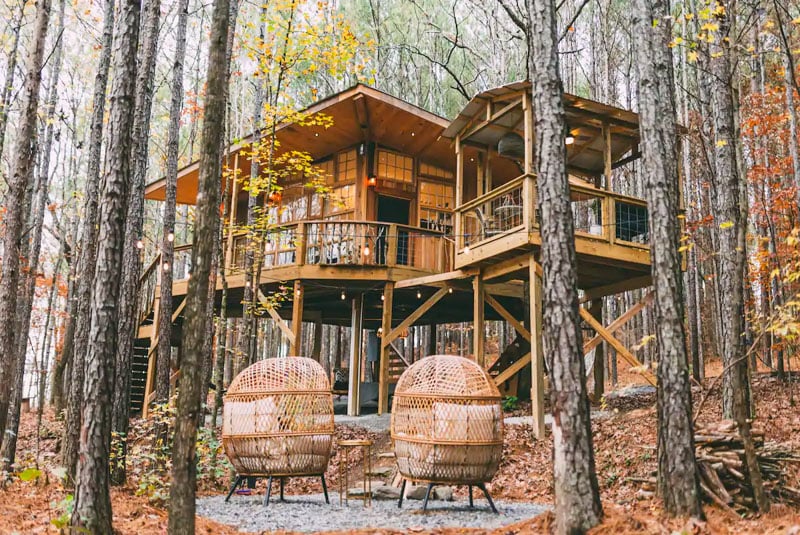 Image showing Wanderlust at Firefly Treehouses, a cozy elevated cabin surrounded by trees.