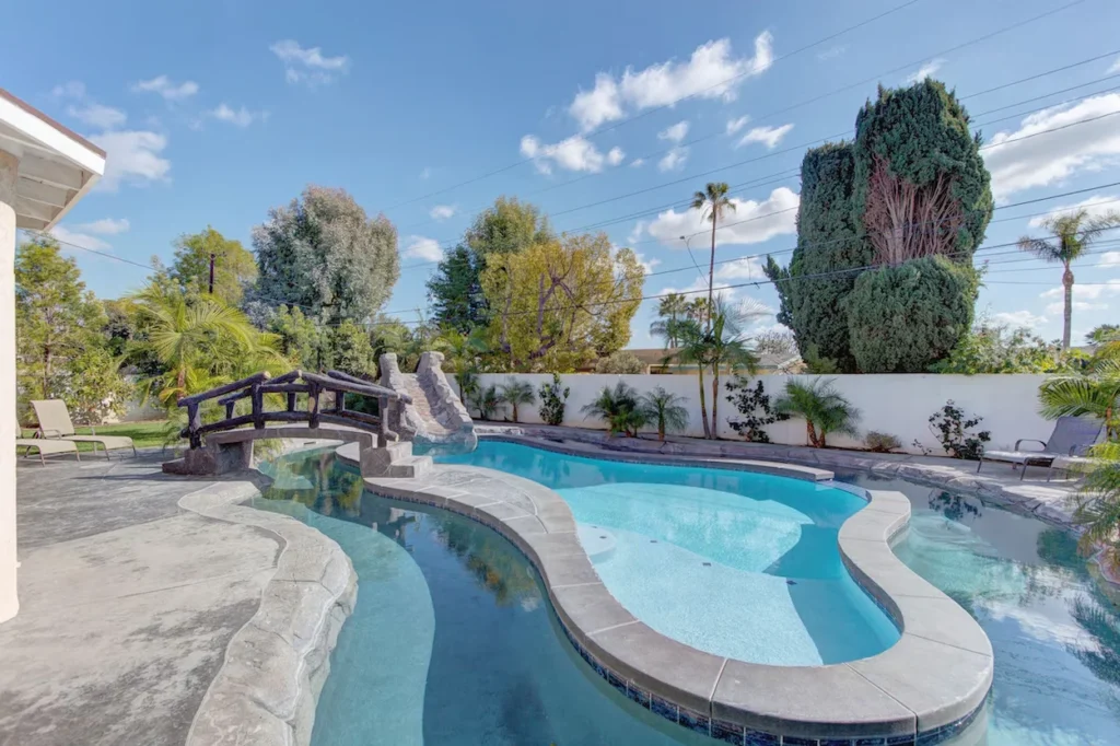 Private backyard pool with a curved lazy river, stone bridge, and rock slide