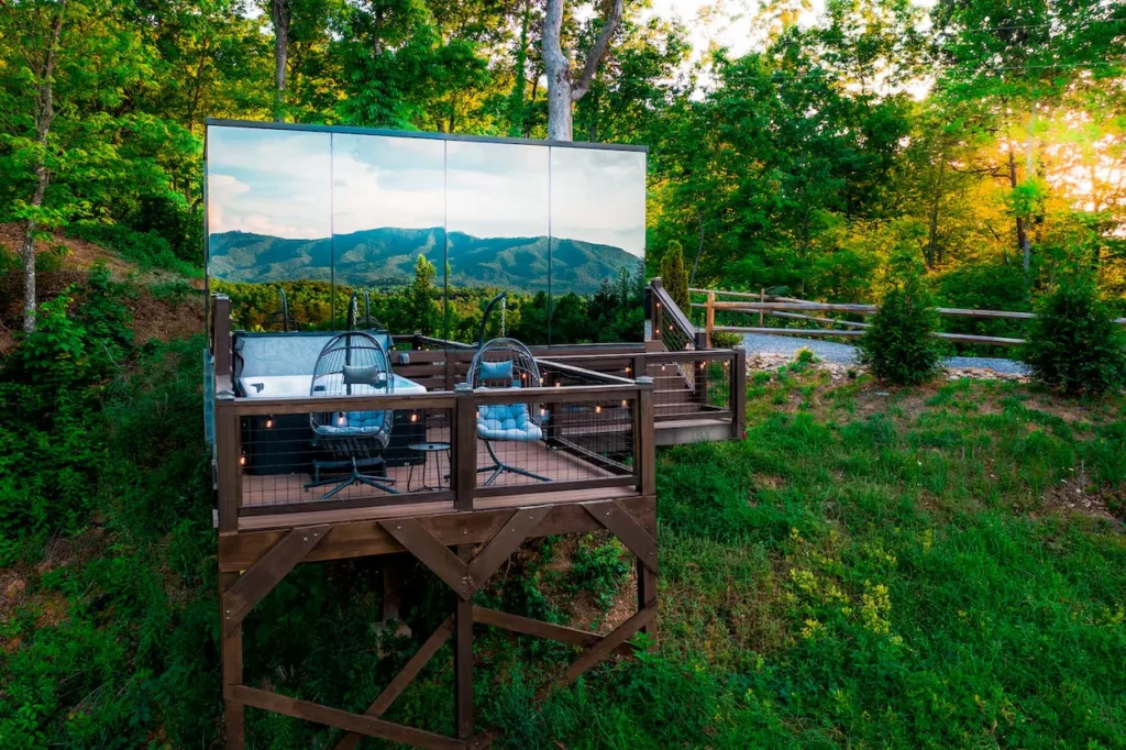Mirrored cabin deck with a hot tub and mountain view