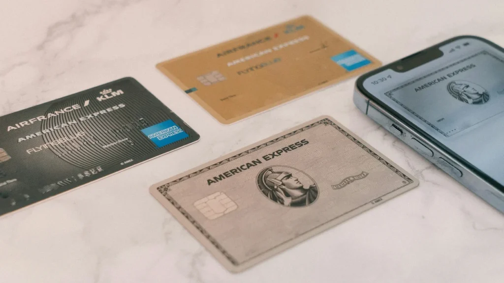 American Express Gold, Platinum, and Air France KLM cards scattered next to an iPhone screen