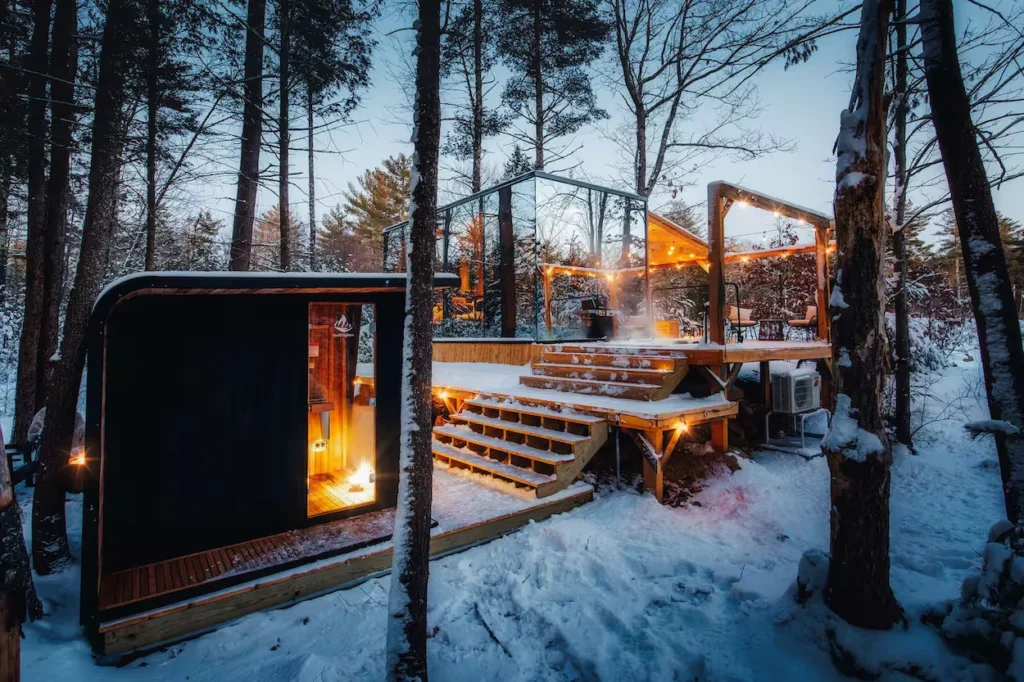 Mirrored glass cabin and modern black sauna in a snowy forest