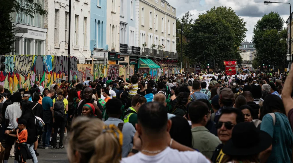 A large crowd packed into a London street lined with colorful houses during Notting Hill Carnival