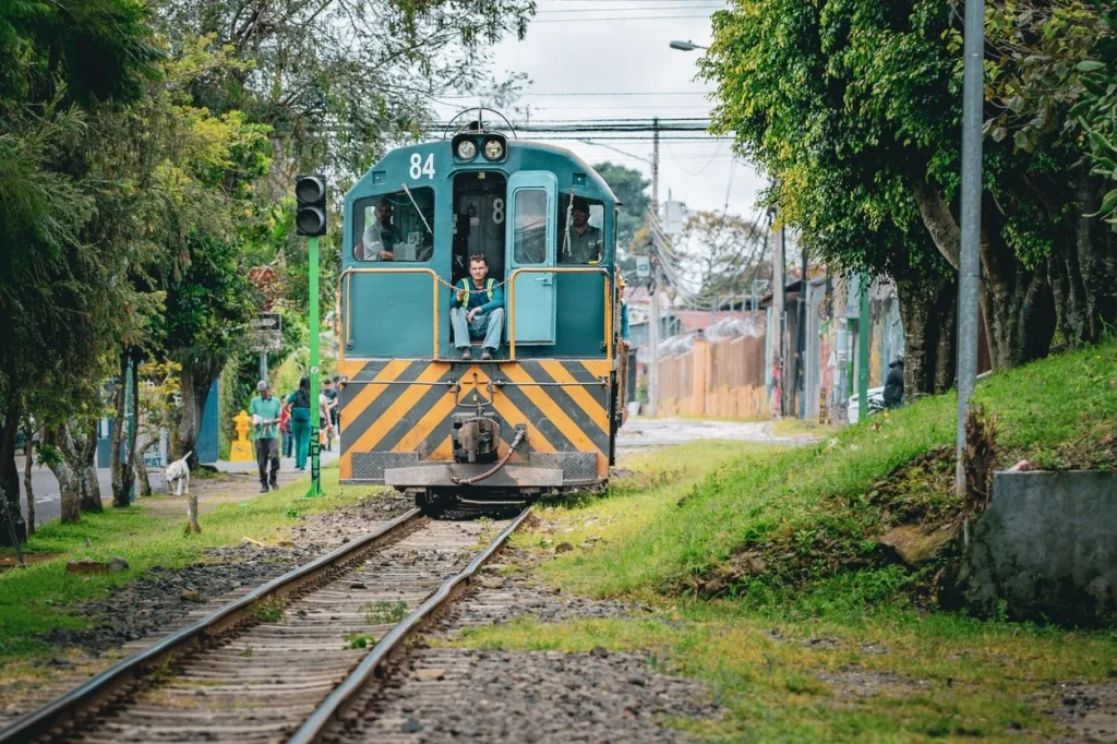A blue and yellow train locomotive on tracks running through an urban area in San Jose