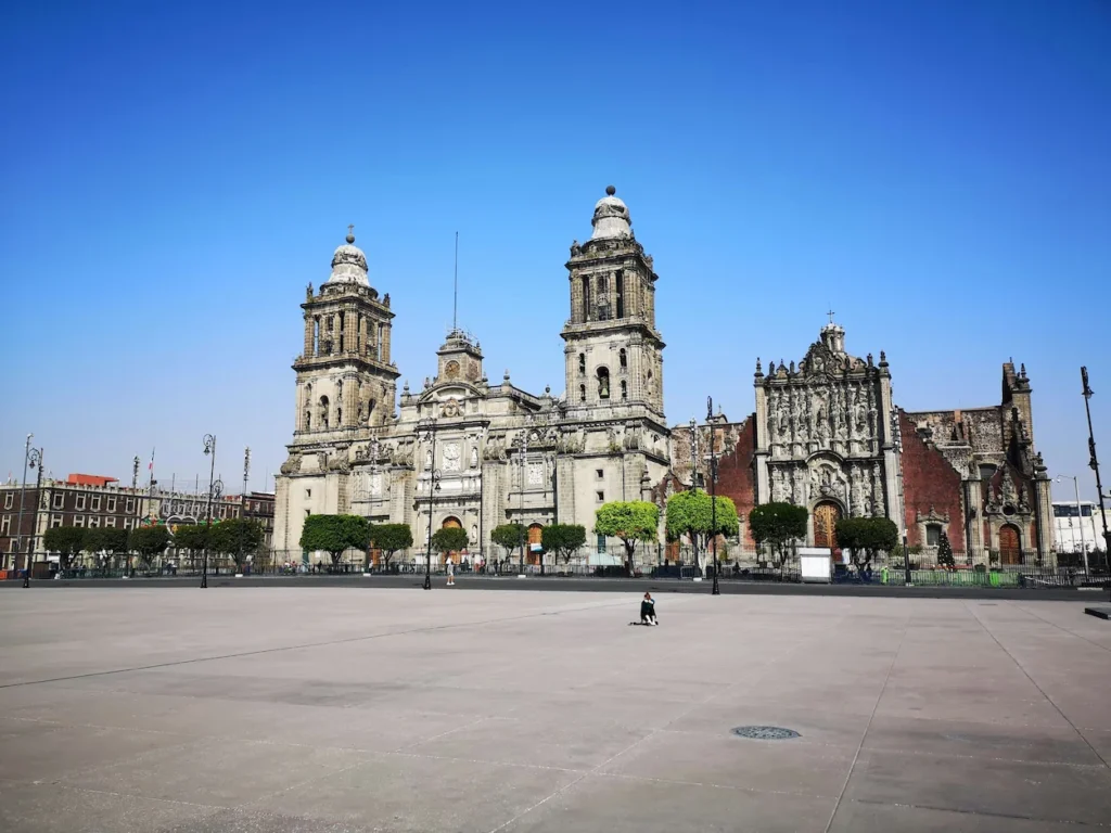 Mexico City Metropolitan Cathedral standing on the edge of a wide, empty concrete plaza