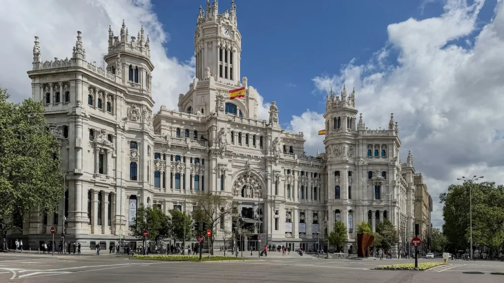 Palacio de Cibeles grand white facade in Madrid under a cloudy blue sky