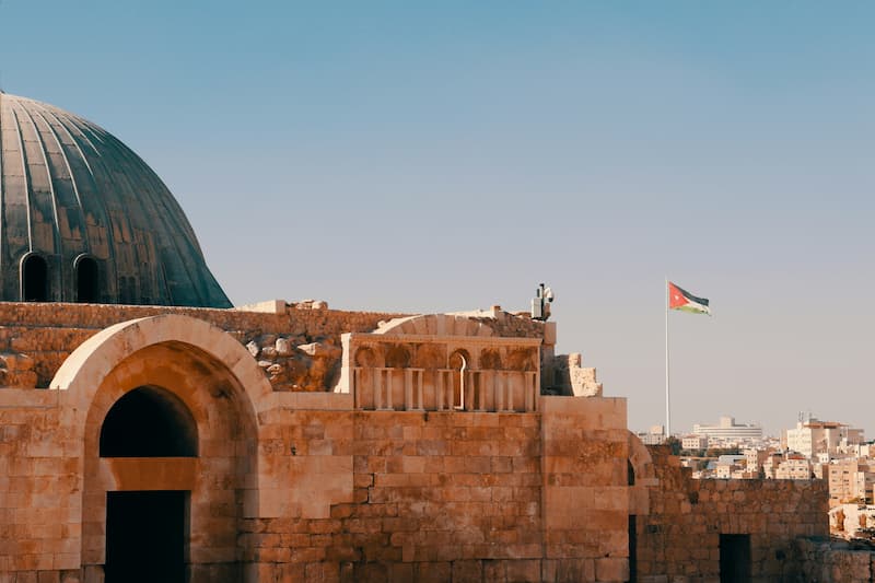 Historic Roman amphitheater in Amman, Jordan, at dusk, with city lights in the background.