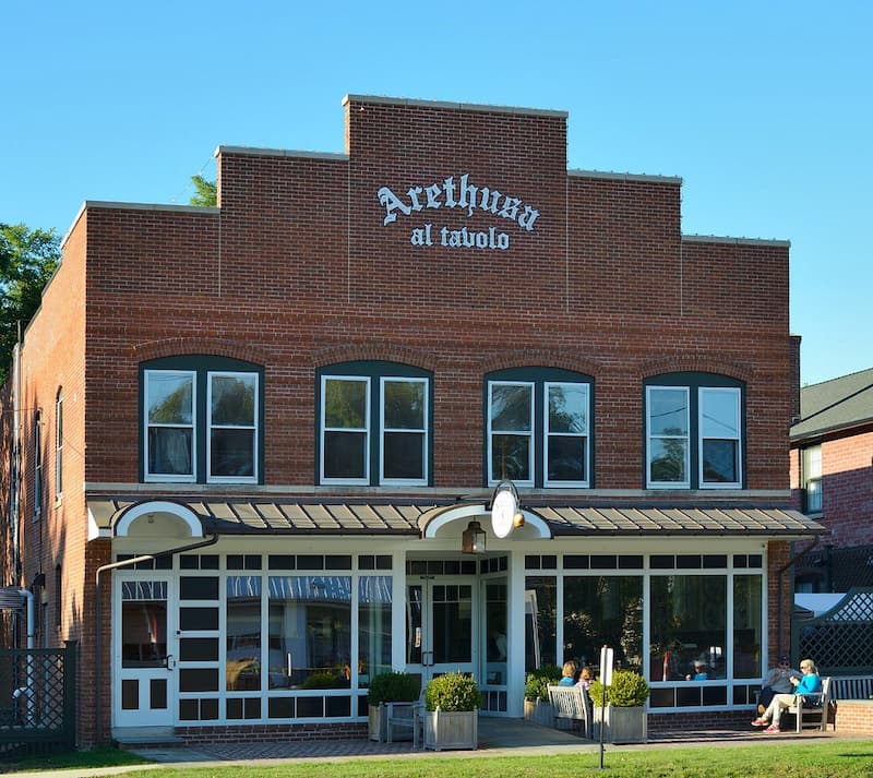 The sunny brick exterior of the two-story building housing Arethusa al Tavolo restaurant.