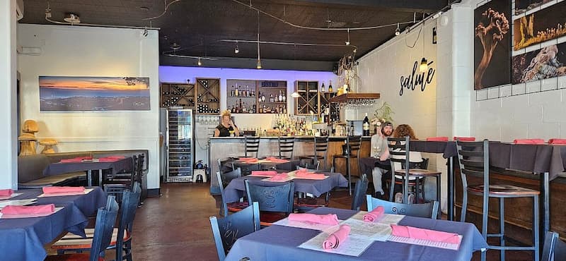 The modern interior of a bistro with set tables and a bar area in the background.